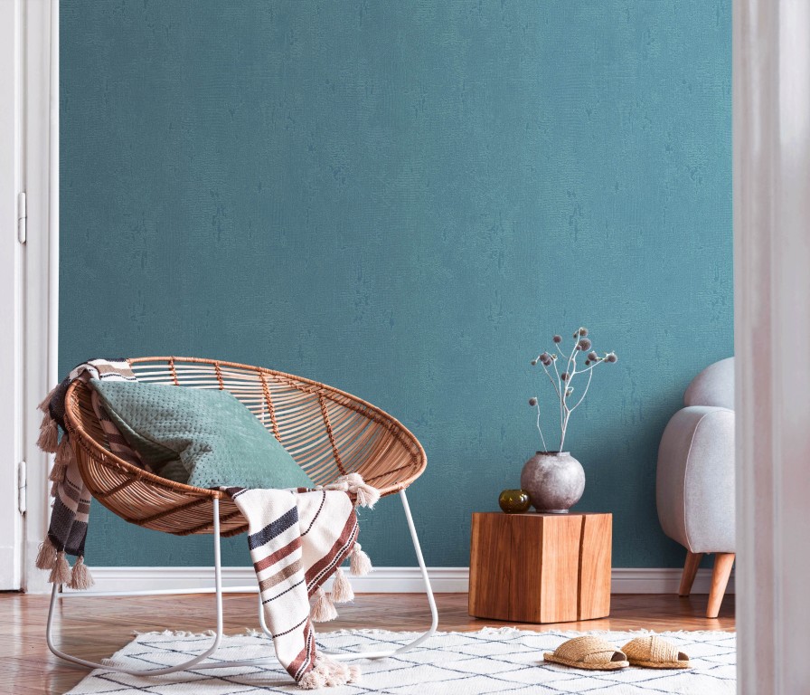 Papier peint bleu de la collection Polygone 2028 en situation avec fauteuil osier