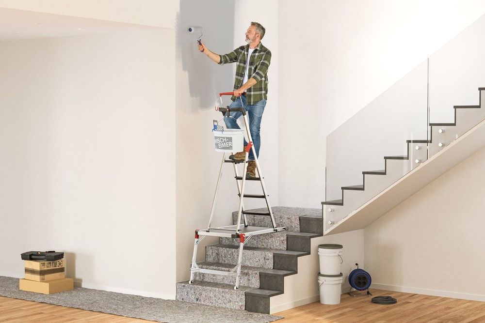 Peintre sur un escabeau placé sur la plateforme Hailo TP2 pro