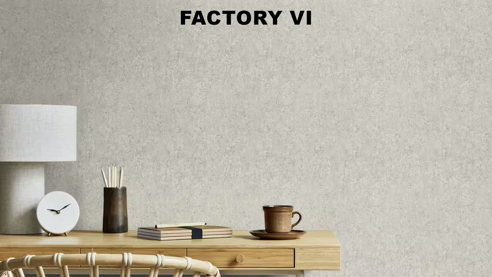 Papier peint gris texturé à effet béton de la collection "Factory VI", installé dans un espace de travail avec un bureau en bois clair, une lampe blanche et des accessoires de papeterie.