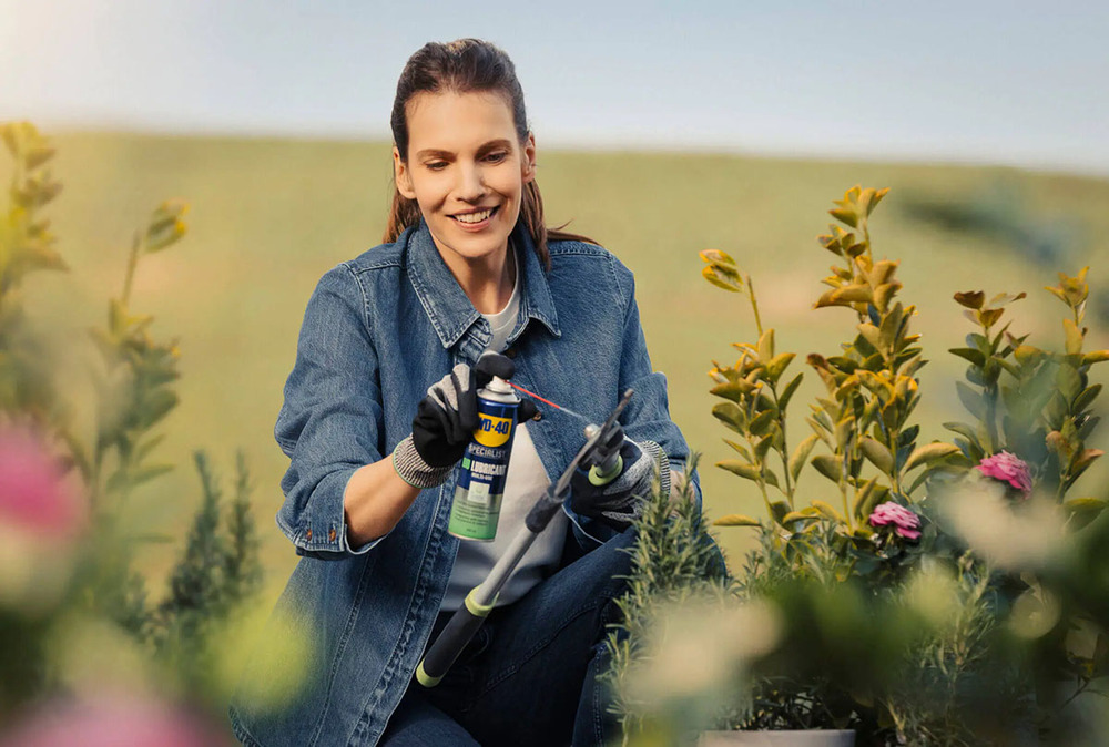 Femme qui utilise le Lubrifiant Dégrippant Bio WD-40 sur une cisaille de jardin